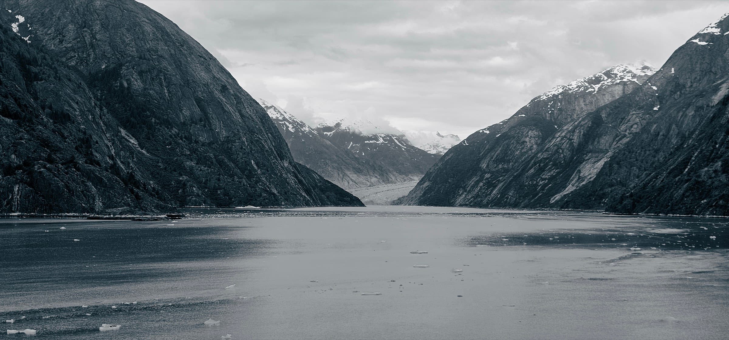 Steep, mist-layered rock walls of a fjord converging toward a distant glacier, Endicott Arm, Alaska.