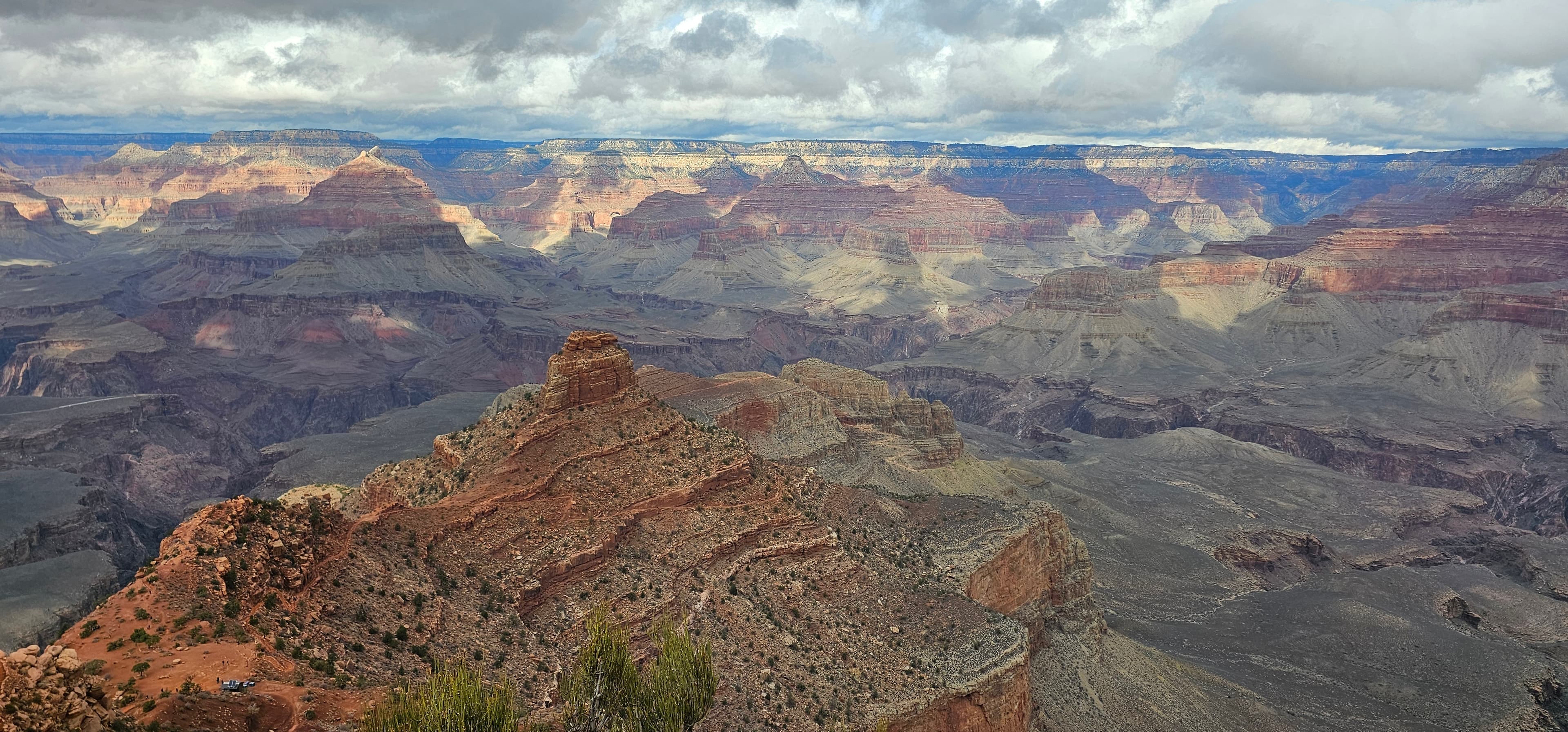 Layered ridges of the Grand Canyon under a heavy clouded sky.